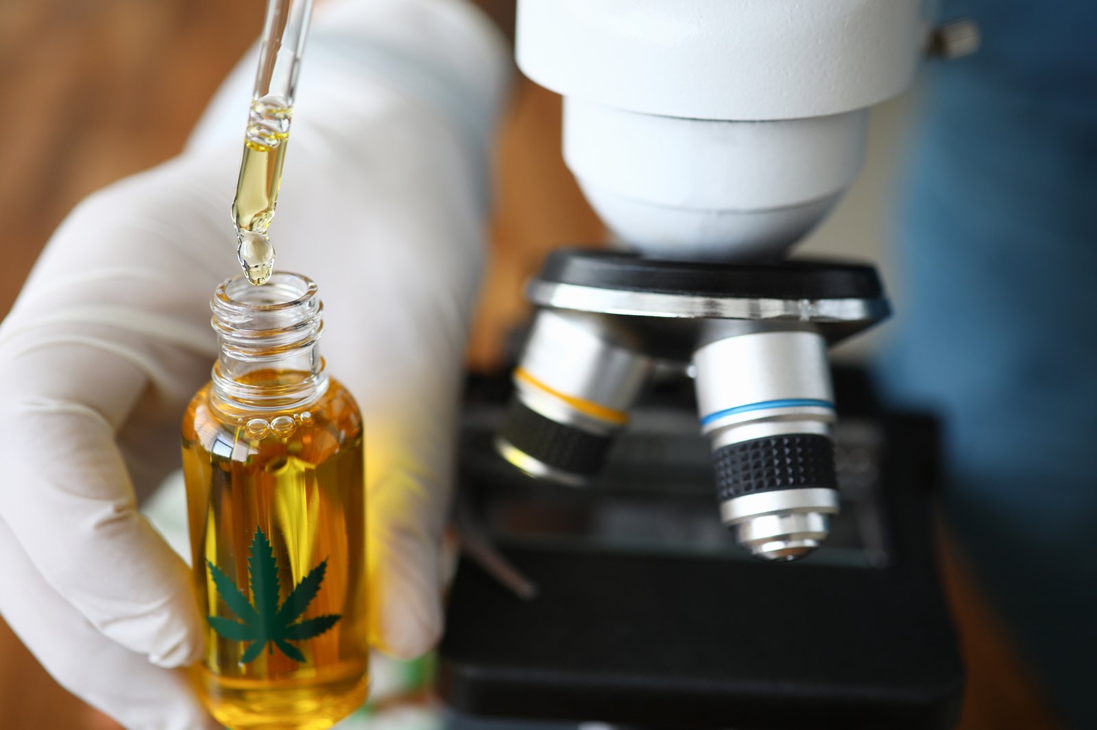 Microscope background with CBD oil droplet container in foreground